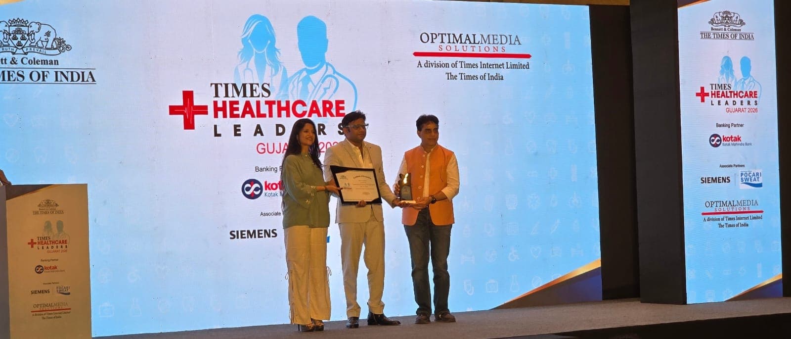 Dr. Manish Saini receiving Times Healthcare Leaders Gujarat 2026 Award on stage with The Times of India branding
